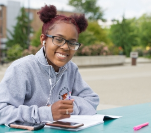 Student with earphones studying at picnic table